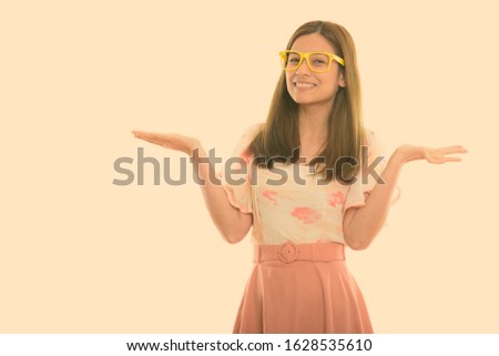 Studio shot of happy young beautiful woman smiling and showing something