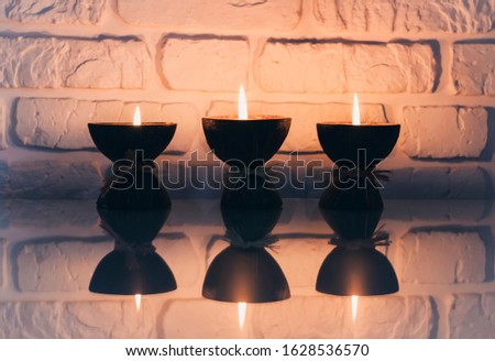 Burning spa aroma candles in coconut shell on a glass white table, cozy home interior