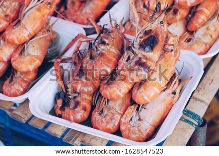 Grilled shrimps on the flaming grill with flames in background in Thailand market