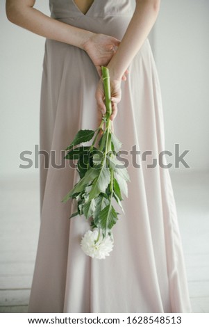 Young Beautiful Girl in a Pink Dress with a Bouquet Holding a Delicate Bouquet of Flowers on a Gray Background