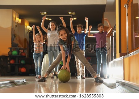 Girl throwing ball and spending time with friends in bowling club