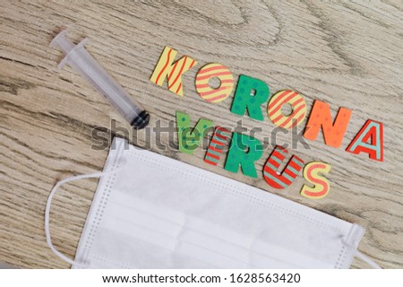 Concept image or Koronavirus containing words (letter) with face mask and syringe over wooden background Royalty-Free Stock Photo #1628563420