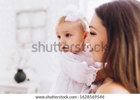 Mom smiles and kisses her daughter. A happy family. Portrait of a mother.