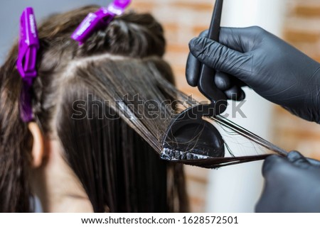 The hairdresser applies professional liquid keratin to the client's hair. Close up. A girl does keratin hair strengthening in a beauty salon. Hair care. Royalty-Free Stock Photo #1628572501