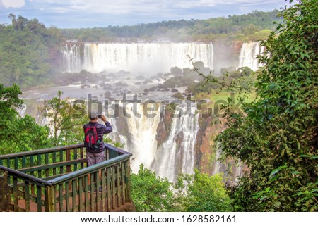 A man takes pictures at Part of The Iguazu Falls seen from the Argentinian National Park. Border of Brazil and Argentina. National Park. South America, Latin America. 