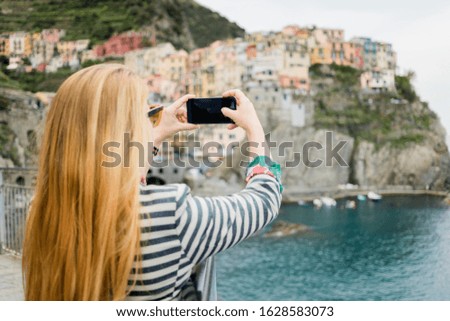 Young woman taking a photo of the village of Cinque Terre, Italy