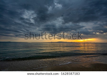 Amazing dramatic greek landscape. Early morning and first sunlight at horizon line of peaceful dark sea water and heavy beautiful grey clouds. Beautiful great natural background. Horizontal photo.