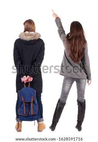 Back view of two pointing young girl in winter jacket. Rear view people collection. backside view of person. beautiful woman friends showing gesture. Rear view. Isolated over white background.