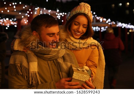 Happy couple with gift box at Christmas fair