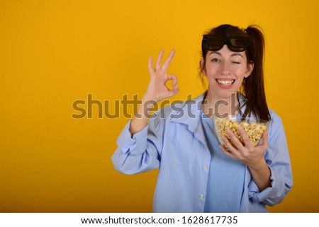 woman with popcorn signs fingers on yellow background