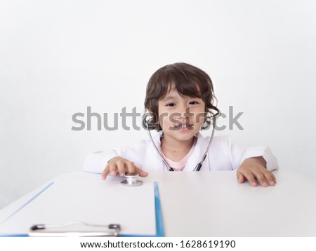 A girl plays a doctor. children's games. In white coat and stethoscope. Adorable child. copy space
