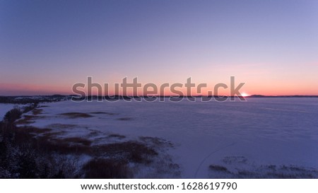 Awesome evening lake sunset. Photo was made in increment winter in Latvia, lake wasfull covered with the ice and snow.
