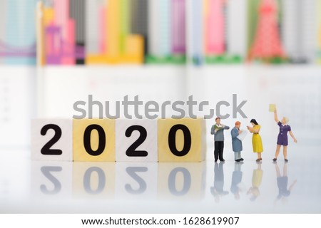 Wooden word number 2020 with business team reading book on blurred city scape and copy space for text using as background business investment, new year, education concept.