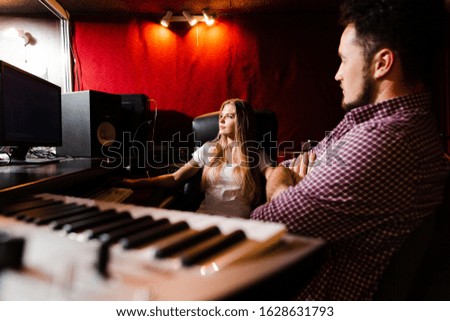Close-up keyboard and people mastering the songs