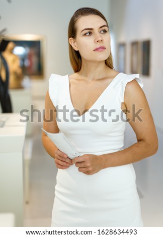 Portrait of thoughtful young woman exploring art pieces in gallery