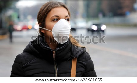 COVID-19 Pandemic Coronavirus Young girl in city street wearing face mask protective for spreading of Coronavirus Disease 2019. Close up of young woman with protective mask on face against SARS-CoV-2. Royalty-Free Stock Photo #1628661055