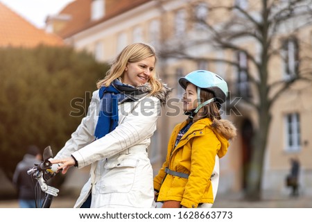 Young woman and her son riding the bicycle in a city
