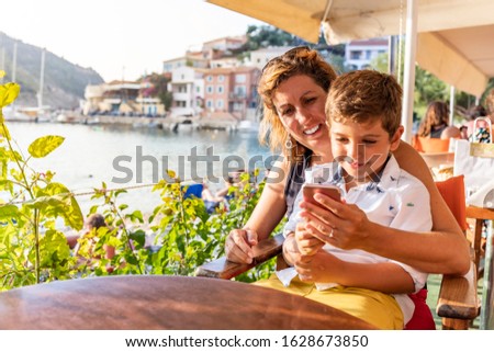 Mother and son sitting on a table usin a mobile phone
