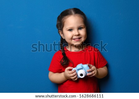 Little photographer with toy camera on blue background