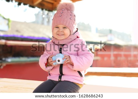 Cute little photographer with toy camera outdoors