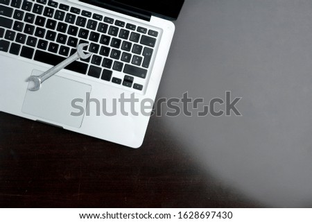 Key on laptop, close-up, on wooden table. Technical support concept