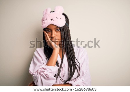 Young african american woman wearing pink pajama and sleep mask over isolated background thinking looking tired and bored with depression problems with crossed arms.