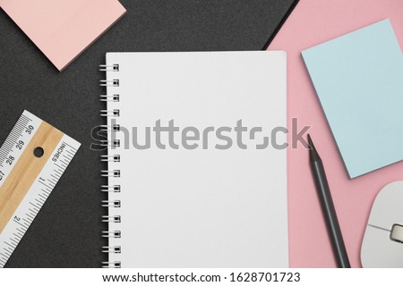 Empty spiral notebook with white pages on a pink background. Pink office desk table with notepad and supplies. Freelancer workplace concept. Mockup