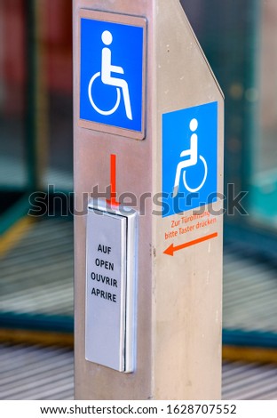 disabled sign at a door opener - translation: please press the button to open the door