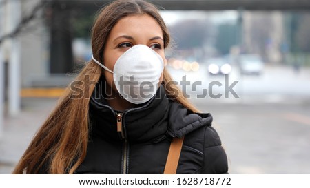 COVID-19 Pandemic Coronavirus Young Girl in city street wearing face mask protective for spreading of Coronavirus Disease 2019. Close up of young woman with protective mask on face against SARS-CoV-2. Royalty-Free Stock Photo #1628718772