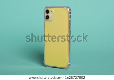 Phone case mock up side view. Yellow iPhone in clear silicone case isolated on green background