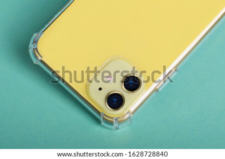 Yellow iPhone 11 isolated on yellow background close up. Smartphone in clear silicone case, phone case mock up