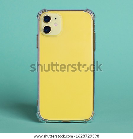 Yellow iPhone 11 in clear silicone case back view isolated on green background. Phone case mockup close up