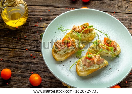 rustic wooden background, top and side, on a plate, appetizer sandwiches with large cod liver, cherry tomatoes, greens