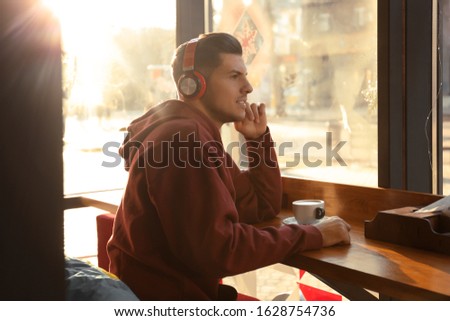 Man listening to audiobook at table in cafe
