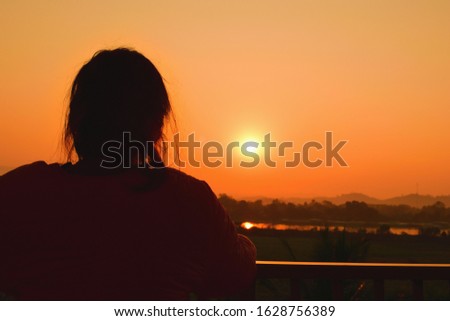 the girl back view is staring at the sun at dawn on a new day