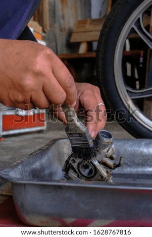 The mechanic cleans the carburetor with dirt.