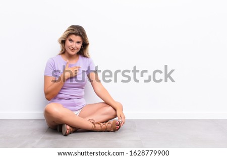 young pretty latin woman looking proud, confident and happy, smiling and pointing to self or making number one sign sitting on the floor