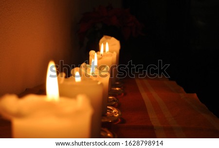 Rows of burning candles in a dim room during christmas time