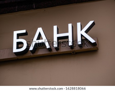 Backlit Bank sign above the entrance. Text in russian is Bank