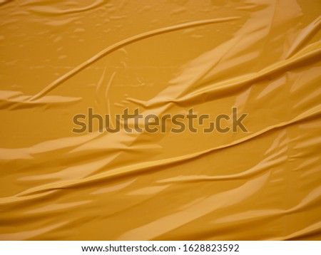 Yellow vinyl film overlapped pieces. Background from a film with a wavy texture glued to the surface
