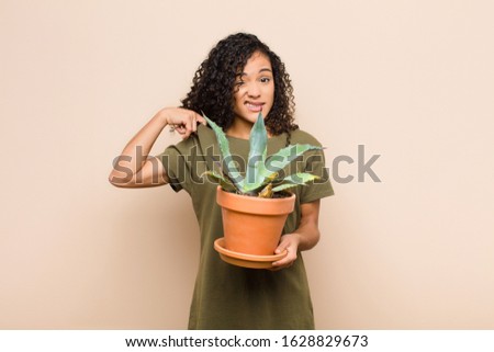 young black woman feeling stressed, anxious, tired and frustrated, pulling shirt neck, looking frustrated with problem holding a cactus