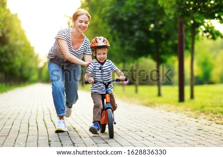 happy family mother teaches child son to ride a bike in the Park in nature
