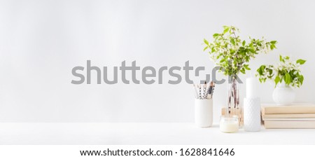 Home interior with decor elements. Spring flowers in a vase, office supplies on a light background