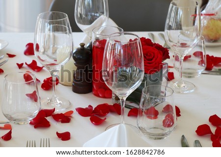 valentine's day special dining table set up with wine glasses and red rose petals
