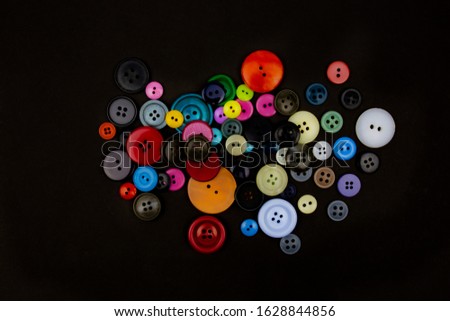 a lot of big and small vintage buttons for clothes on a black background