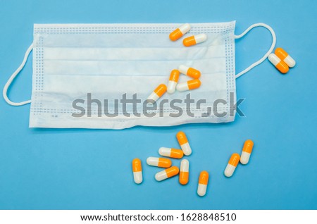Medical mask, orange-white capsules on a blue background close-up
