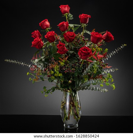 Studio photography of floral arrangements on a gray backdrop with a dozen red roses Royalty-Free Stock Photo #1628850424