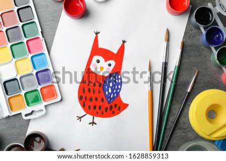 Flat lay composition with child's painting of owl on grey table