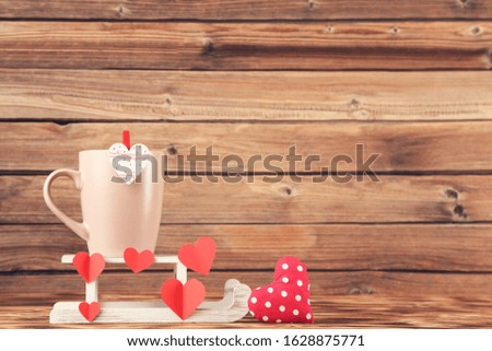 Fabric and paper hearts with cup and white sleigh on brown wooden table