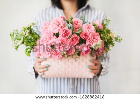Woman holding a basket with beautiful flowers. Closeup picture